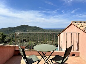 Ein Balkon mit Tisch und Stühlen, der Blick auf eine Berglandschaft bietet.