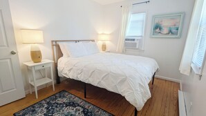 Makuuhuone, jossa on sänky, yöpöydät, matto ja ikkuna, jossa on verhot.