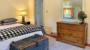 Een slaapkamer met een bed, een dressoir, een spiegel en een lamp.
