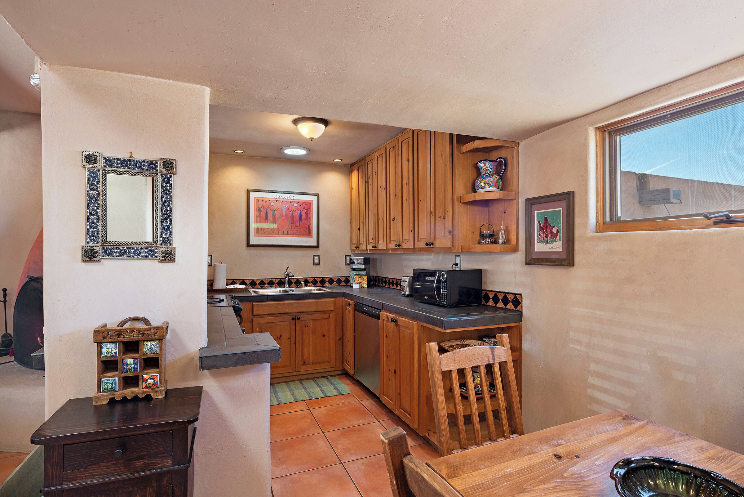 A compact kitchen with wooden cabinets, a microwave, and a dining area with a table and chairs.