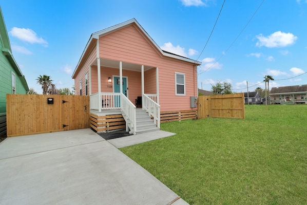 A pink house with a porch and a wooden fence.
