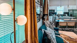 Ein modernes Wohnzimmer mit einer Couch, einer Skelett-Dekoration und einem Essbereich mit Stühlen.