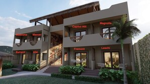 Un hotel moderno de varios pisos con balcones y un jardín tropical.