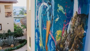 Un pasillo con un cuadro abstracto de gran tamaño en la pared, vistas al océano y un edificio con tejado de tejas.