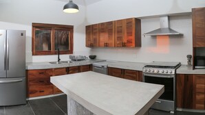 Una cocina moderna con armarios de madera, un refrigerador de acero inoxidable, horno empotrado y una isla grande.