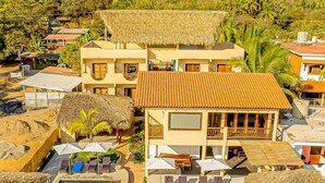 Un complejo turístico con piscina, edificaciones de techo de paja y palmeras.