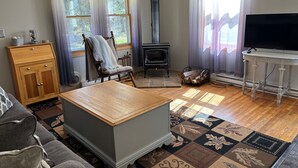 A living room with a fireplace, a sofa, a wooden coffee table, and a television on a stand.