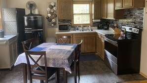 A compact kitchen with wooden cabinets, a built-in microwave, a gas stove, and a refrigerator.