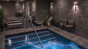 A pool area with a diving board, lounge chairs, and a small table with a candle.