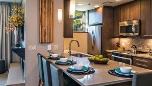 A modern kitchen with dark wooden cabinets, stainless steel appliances, and a central island with seating.