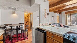 A compact kitchen with a dining area, a built-in oven, and a small refrigerator. - Fort Marcy 90 | Walk to Plaza | Full Kitchen | Private Bedroom | Hot Tub | Pool | Single Level (Santa Fe)