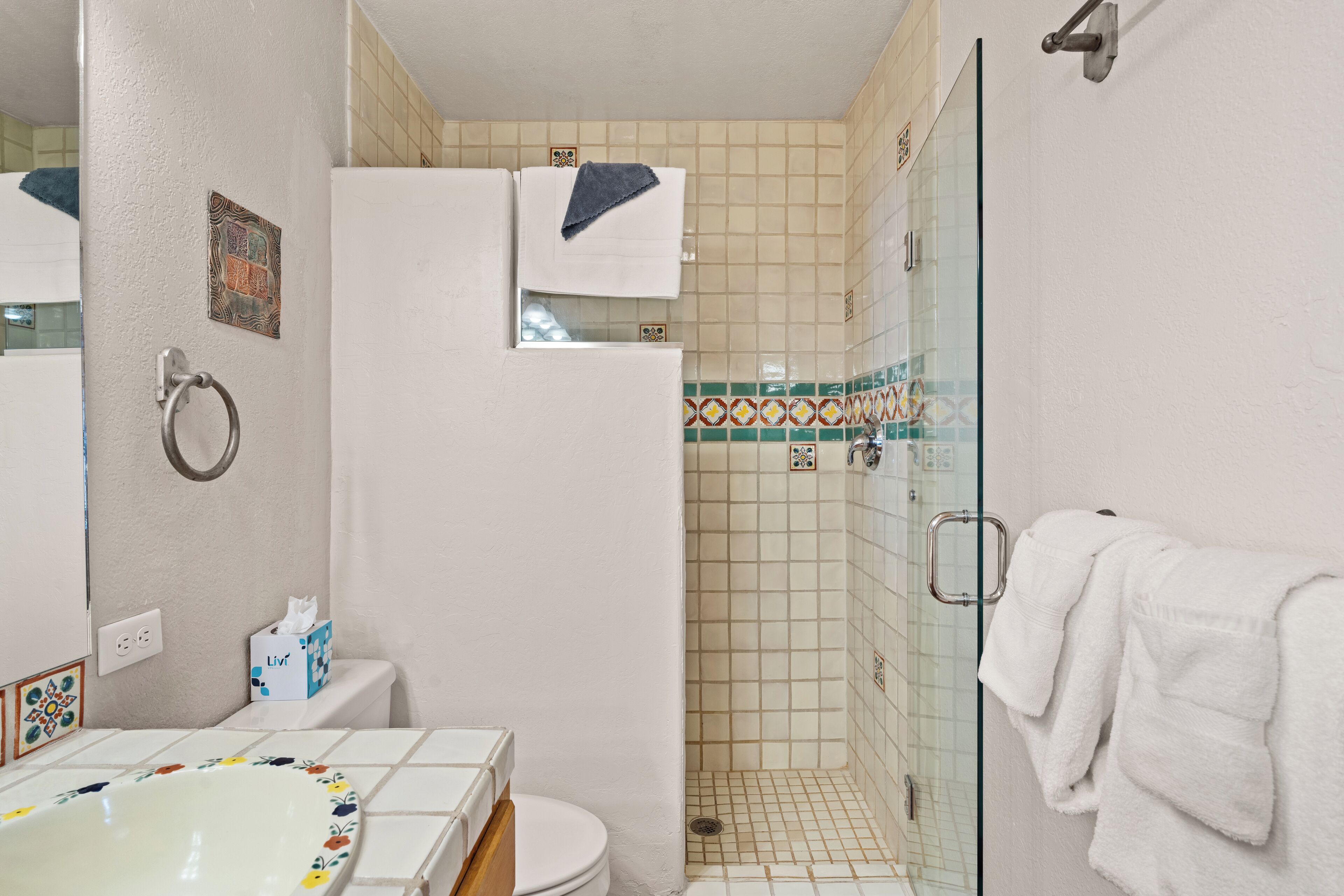 Une salle de bain comprenant des toilettes, une douche avec une porte en verre et un lavabo agrémenté d’un receveur décoratif.