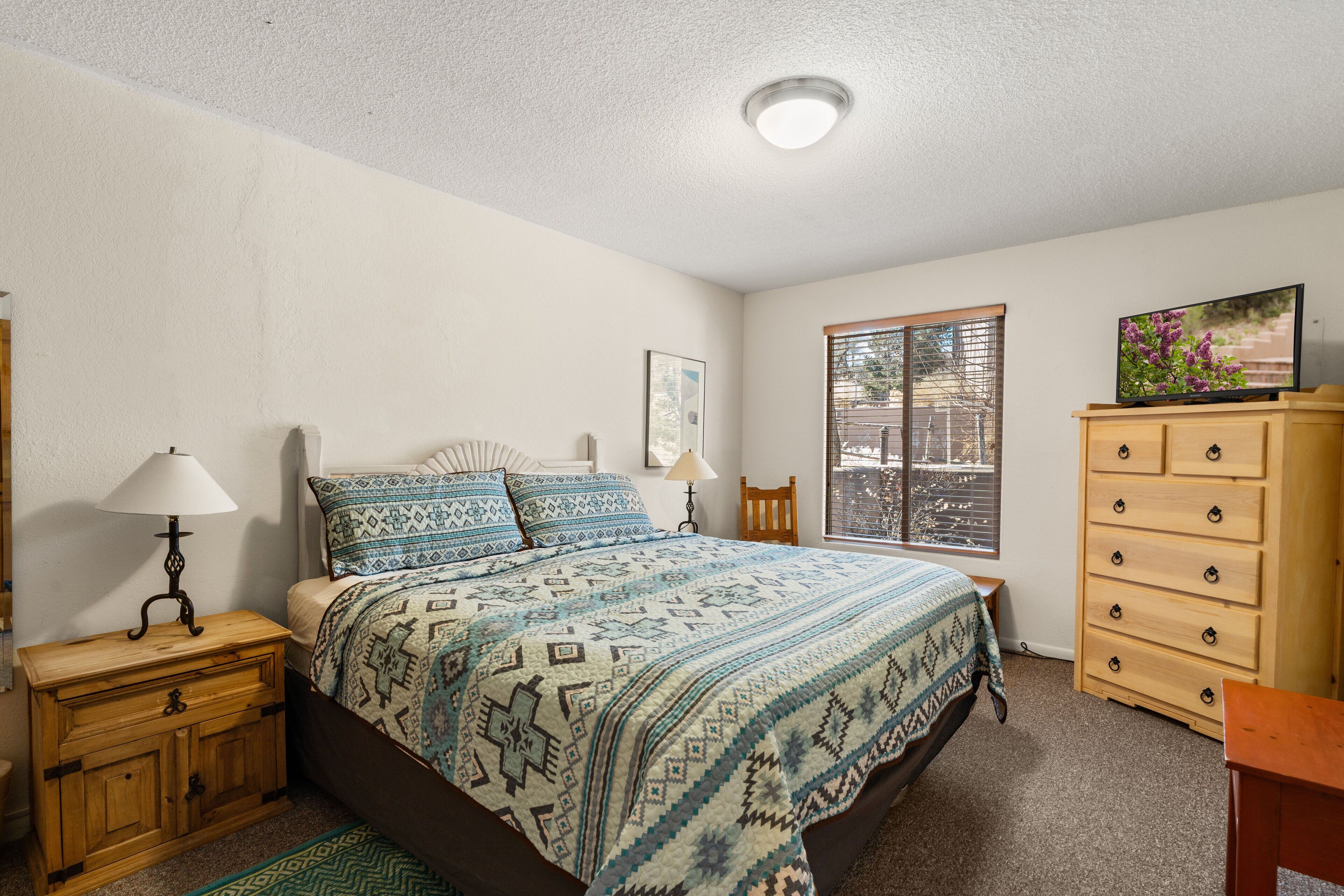 Une chambre à coucher avec un lit, une commode en bois et un téléviseur posé sur un meuble.