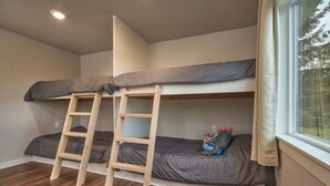 A bunk bed room with a wooden ladder, a window with curtains, and a view of trees outside. - Riverfront Cottage with Hot Tub 1/4 mi from Beach (Brookings)