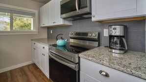 A modern kitchen with stainless steel appliances, a microwave, an oven, and a coffee maker. - Riverfront Cottage with Hot Tub 1/4 mi from Beach (Brookings)