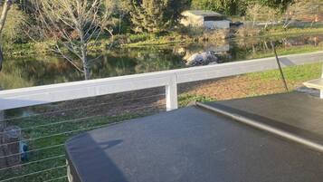 A view from a balcony overlooking a lake with a wooden deck and a white railing.