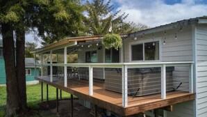 A two-story house with a wooden deck and a hanging plant. - Riverfront Cottage with Hot Tub 1/4 mi from Beach (Brookings)