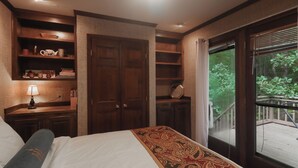 Un dormitorio con una cama grande, una mesita de noche, un aparador y un ventanal con vistas a una terraza de madera.