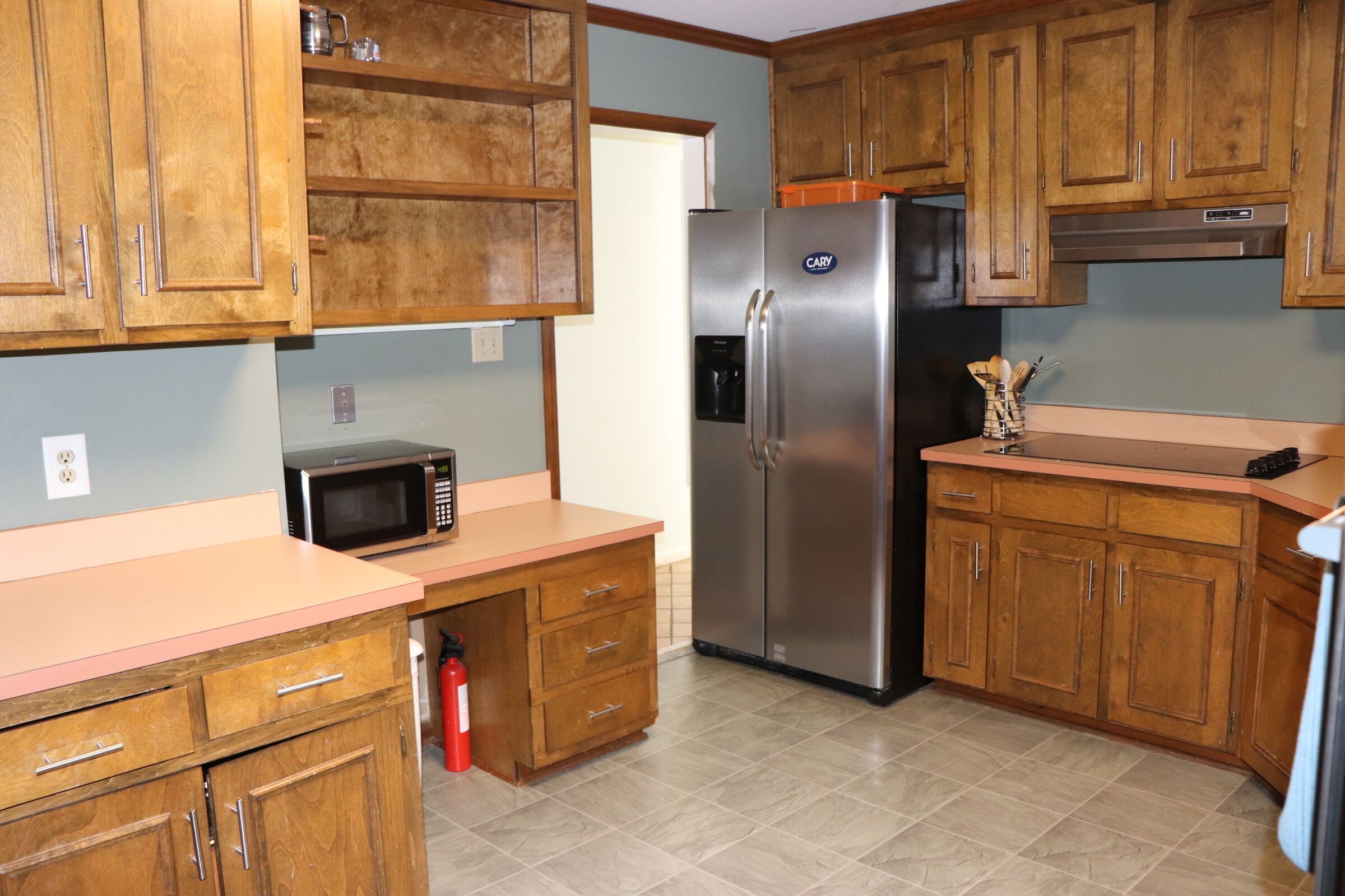 A kitchen with wooden cabinets, a stainless steel refrigerator, a microwave, and a countertop.
