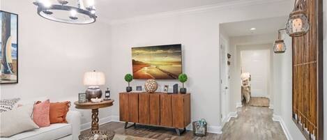 Un salon moderne avec une table basse en verre, un meuble en bois et un grand tableau accroché au mur.