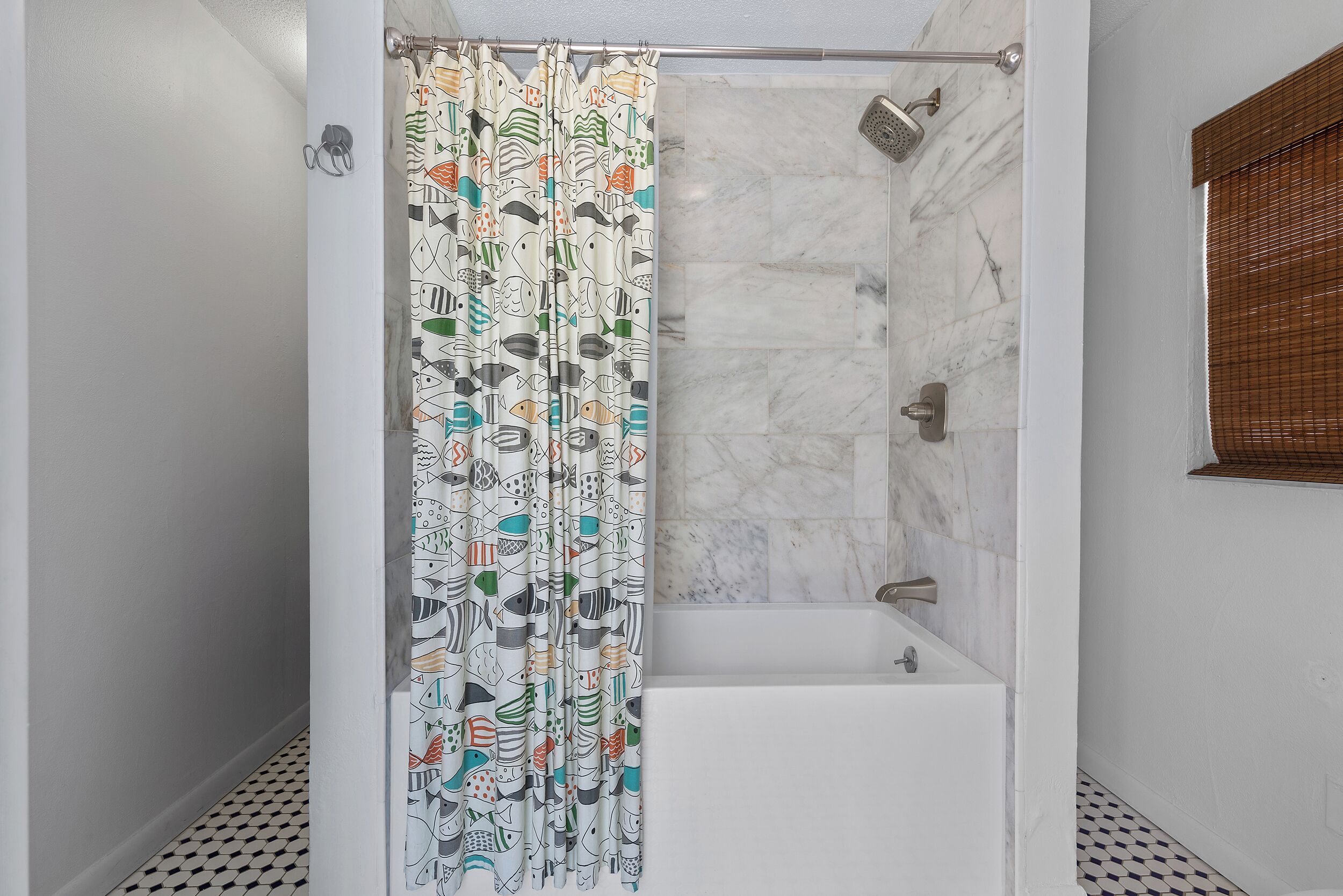 A shower with a patterned curtain, a bathtub, and a tiled floor.