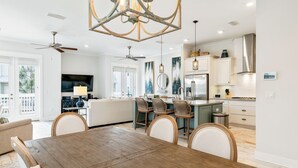 A spacious kitchen with a dining area, featuring a wooden table and chairs, pendant lights, and a ceiling fan. - 30A Top Rated! Free Golf Cart+Bikes+2 Pools+Bunks (Inlet Beach)