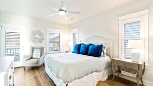 Une chambre à coucher comprenant un lit, une chaise, une table de chevet et un ventilateur de plafond.