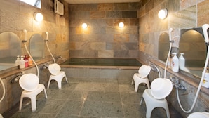 Un baño moderno con una bañera grande, dos lavamanos y tres sillas blancas.