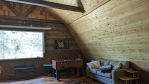 Ein gemütliches Zimmer mit einem Kicker, einer Couch und einem Dartboard.