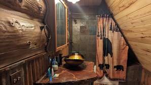 Ein rustikales Badezimmer mit einem Holzbadezimmermöbel, einem großen Waschbecken und einer Duschvorhang mit Tiermotiven.