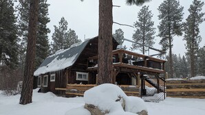 Eine rustikale Holzhütte mit Veranda und einer Treppe, die zu einem oberen Stockwerk führt.