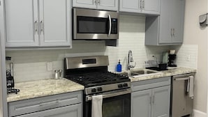 Una cocina moderna con armarios grises, electrodomésticos de acero inoxidable y salpicadero de mármol.