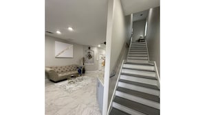 Una sala de estar moderna con un sofá seccional color beige, una mesa de centro y una escalera que sube a otro nivel.