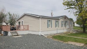 Une maison mobile de plain-pied avec un porche et une petite terrasse.