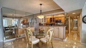 A spacious kitchen with a central island, modern appliances, and a dining area with a glass table and chairs. - Gorgeous 2/2 condo with fantastic views 1402 (Clearwater)