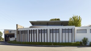 A modern building with a flat roof, large windows, and a sign for 'SignSave'. - Blue Gums Hotel (Fairview Park)