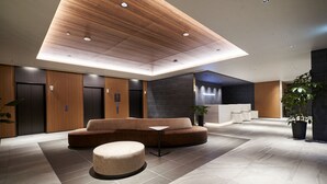 A modern lobby with a wooden ceiling, a sofa, a small table, and a potted plant.