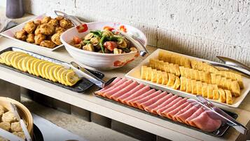 A buffet table with various food items including sliced ham, fried items, and a salad.