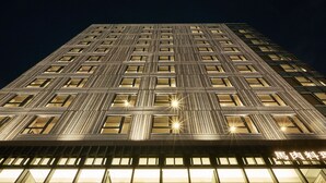 A high-rise building with a grid of windows and a sign at the bottom.