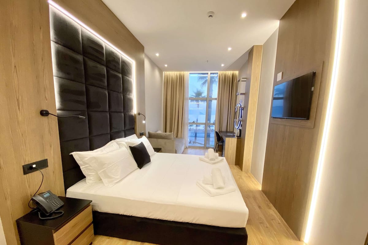 Une chambre d’hôtel moderne avec un grand lit, un téléphone sur la table de chevet et un téléviseur fixé au mur.