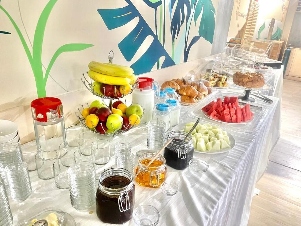 A buffet table with various food items and condiments, including fruits, pastries, and beverages.