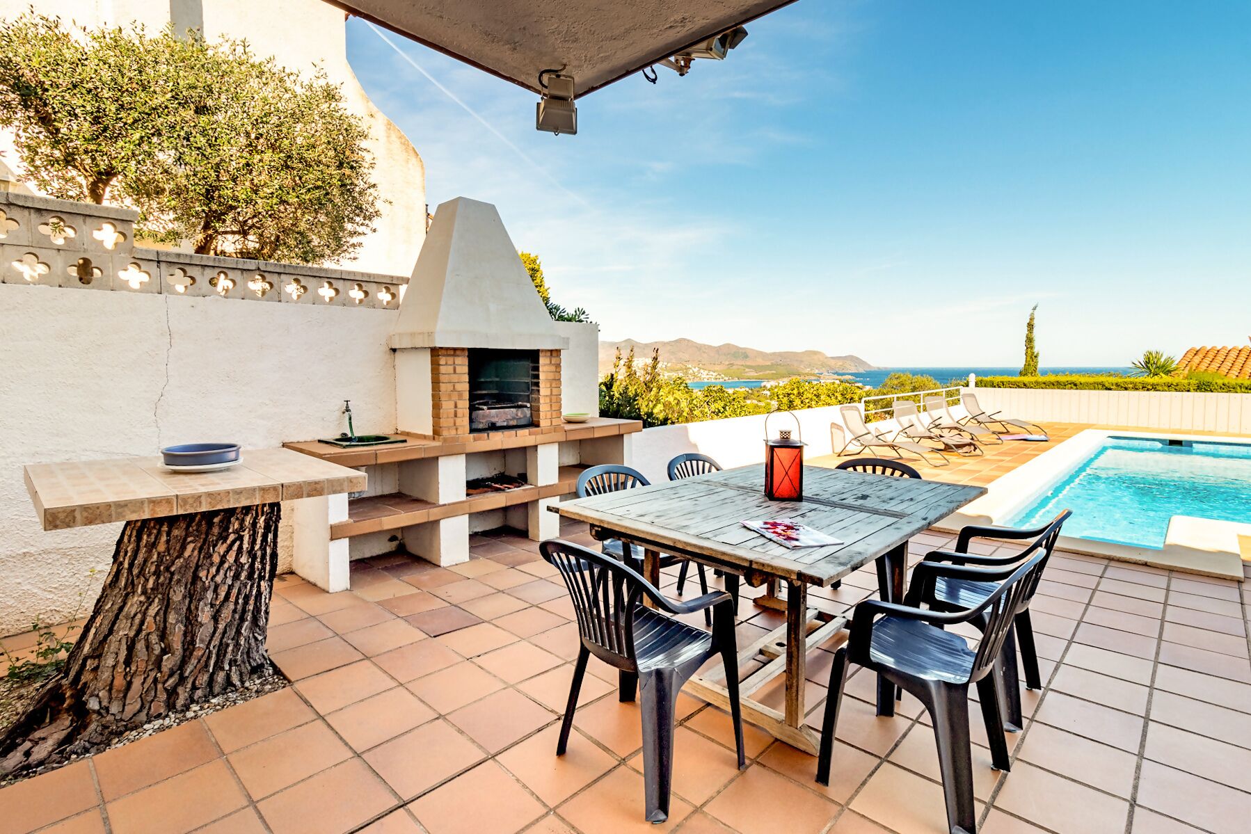 Une terrasse extérieure équipée d’un barbecue, d’une piscine et d’un espace salon.