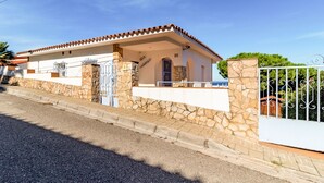Una villa con fachada de piedra, techo de tejas y entrada protegida por una reja.