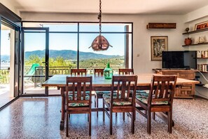 Un coin repas avec une grande table et des chaises, un téléviseur et une bibliothèque.