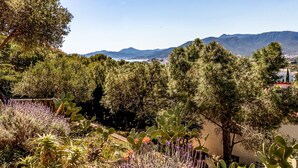A garden with cacti and lavender, a pathway, and a view of mountains and a town in the distance. - Grifeu 08 - Apartment with outside terrace (Llança)