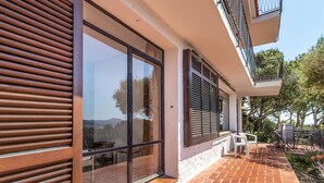 A modern building with large sliding glass doors, a brick patio, and a balcony with outdoor furniture. - Grifeu 08 - Apartment with outside terrace (Llança)