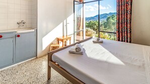 A bedroom with a bed, a window with a view of mountains, a sink, and a cabinet. - Grifeu 08 - Apartment with outside terrace (Llança)