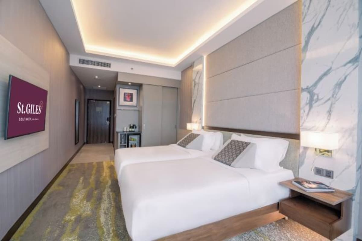 A hotel room with two beds, a TV mounted on the wall, and a marble accent wall.
