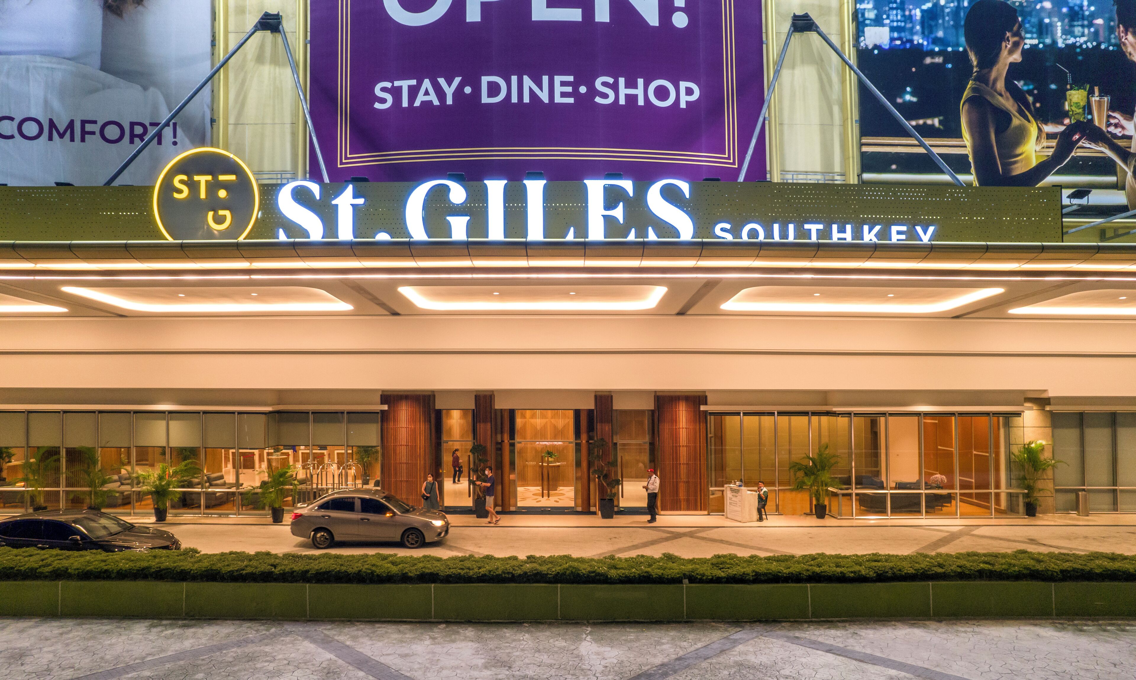 A hotel entrance with a sign reading "St. Giles Southkey" and a neon sign indicating "Stay - Dine - Shop".