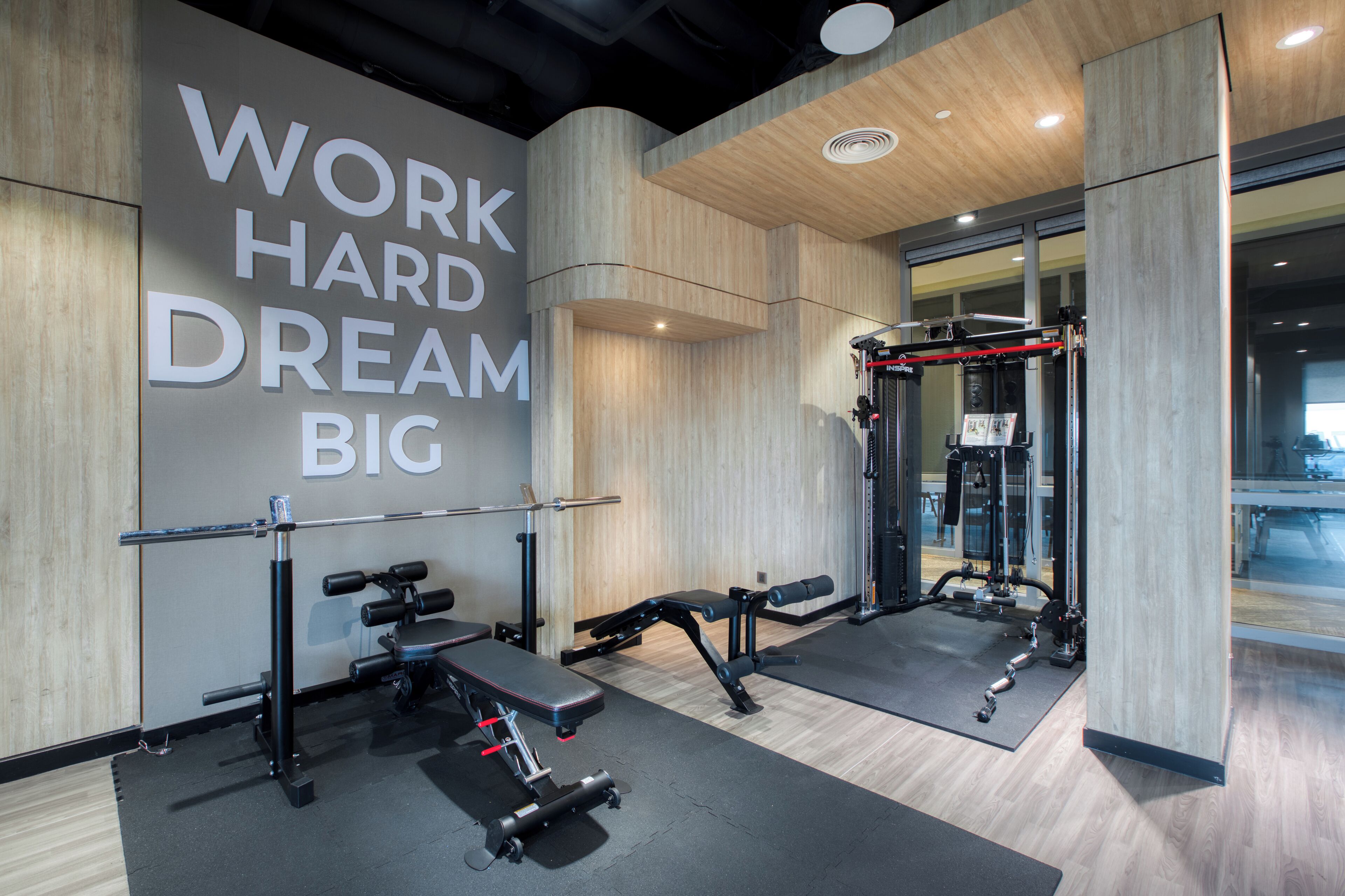 A gym with exercise equipment, a motivational wall, and wooden flooring.